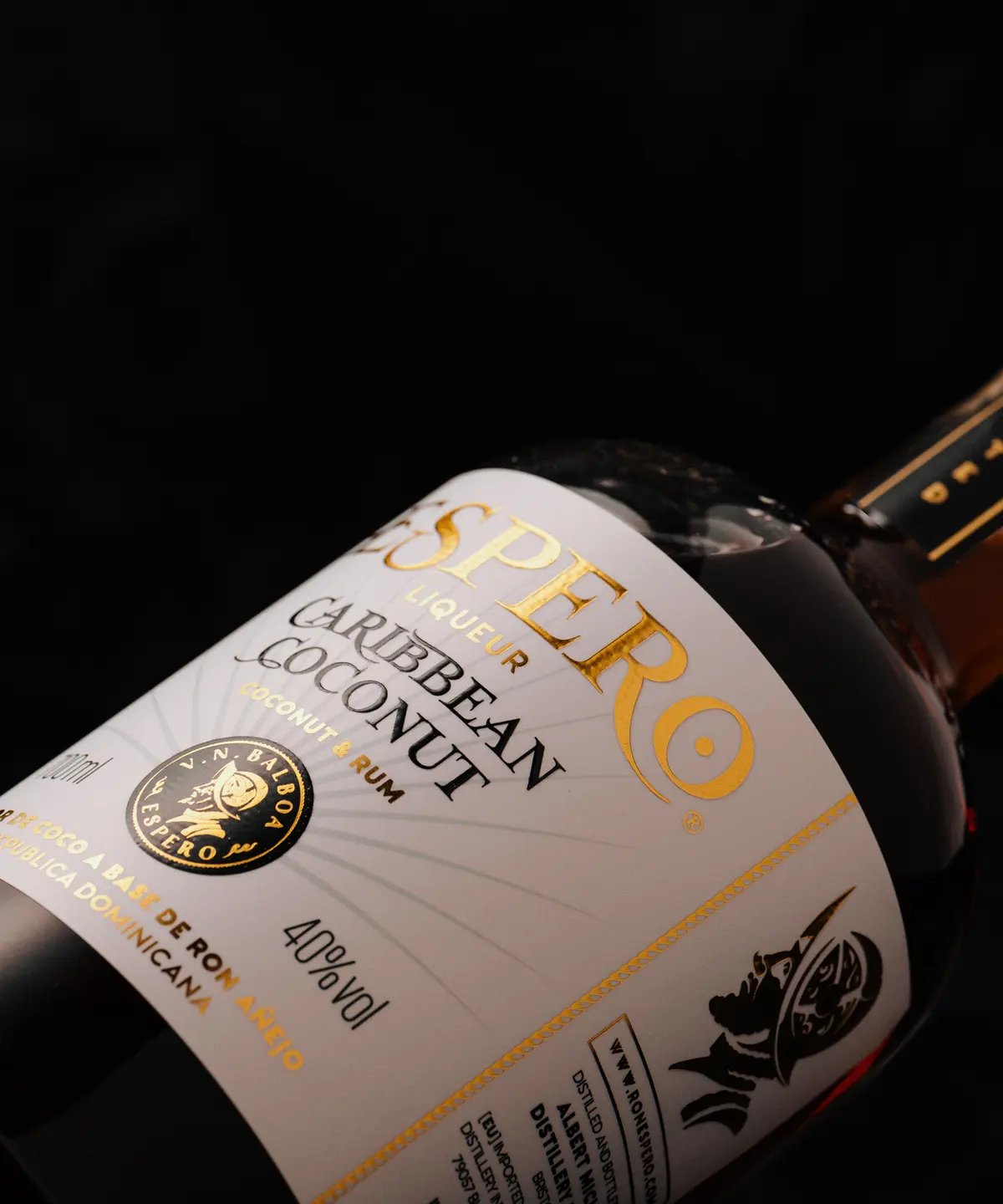 Detail etikety Espero Caribbean Coconut na tmavém pozadí se zlatým potiskem.